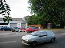 Road with car dealership on far side.
Low workshop building with pitched roof.
Telephone box.
Roadsign marking border of Buckinghamshire.