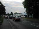 The A4 Bath Road approaching Maidenhead Bridge.
Large trees on left.
Queue of cars.
VW car dealership on right with cars on forecourt.
Part of the disused Skindles Hotel visible in the background.
Large trees on right.