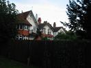 Dark fence with houses behind.
Houses have mixture of white painted and red tile-hung facade.
Dark tile roofs.