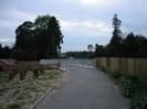 Tarmac footpath leading to pedestrian bridge across the Jubilee River.
Bridge has galvanised metal railings both sides.
Trees on far side of river.
Newly-planted trees in verge on left.