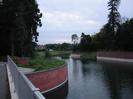 Jubilee River (Maidenhead, Windsor and Eton Flood Alleviation Scheme).
The river runs between brick walls in the foreground, opening out to graded banks in the distance. Walls are of dark red brick with purple-gray capstones.
Galvanised metal railings along pedestrian bridge in lower-left corner.
Large trees each side of river.
Hotel building visible in the distance.