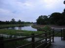 Footpath entrance.
Wooden rail fence and tubular-steel kissing-gate.
Path sufaced with grey chippings.
Grassy area with river beyond.
New planting on both sides of river.
Wooden footbridge in the distance.
Chimneys of Taplow Paper Mill visible on the horizon.
