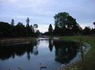 River with swans and canoe.
New planting on both banks.
Large trees in the distance.