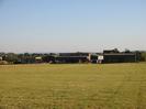 Grassy field with farm buildings.