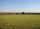 Grassy field.
Houses and trees in the distance.