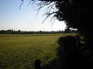 Grassy field with wire fence.
Footpath and trees on right.