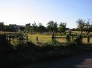 Road with fence.
Open field with house beyond.