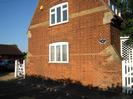 The end wall of The Old Reading Room.
Red bricks with details in sandy-coloured brick.
Unusual butresses at the corners.
White window-frames and gates.
Cast-iron nameplate.
