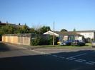 The junction of Hitcham Road and Hanbury Close.
High wooden fence on the left with trellis on top.
Bungalow with grey tile roof on the right.