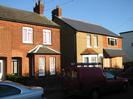 Row of red brick houses; one with pebbledash rendering.