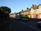 Looking north on Hitcham Road.
Dark hedge and footway on left.
Houses on the right, mostly in red brick with grey roofs.