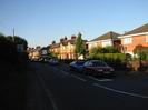 Looking north on Hitcham Road.
Footway and dark bushes on the left.
Houses on the right.