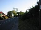 Looking south on Hitcham Road.
Courage brewery sign on the left.
Footway with bus-stop and dark hedge on the right.