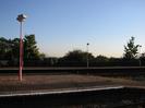 Railway platform with red lamp-posts.
Trees beyond far platform.