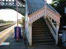 Steps to footbridge.
Bridge has inset GWR logo and other decorative features.
Railway lines on left.