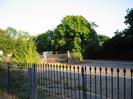 Blue and white iron railings.
Car-park.
Fence and trees beyond.