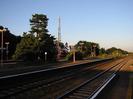 Island platform with large mirror on pole.
Red lamp-posts.
Large Scots Pine tree and cellphone mast in background.