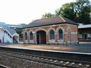 Island platform with building and steps to footbridge on left.
