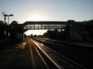 Looking west along platform 1 into the setting sun.
Iron lattice footbridge seen in silhouette.
Light glinting from main line rails.