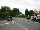 Road junction with cars.
Trees on left.
Cars on display on right.