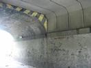 Under railway bridge.
Bridge is in two sections. Both have brick walls.
The near section has concrete deck beams.
The far section has a brick arch.