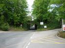 Road junction with rail bridge in the background.
Trees on each side of road.
Signs.