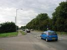 Road junction.
Trees and bushes on both sides of road.
Pavement on left of A4, with bus-stop.
Sign in distance 'Services 1/2m'