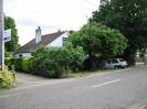 Road with houses on far side.
Nearest house has white painted walls and dark tiled roof.