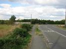 Field and low hedge on left.
Footway and road on right.
SLOW painted on road.
Two chevron signs warning of sharp bend to the right.