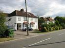 Pair of white semi-detached houses.
Road in foreground.
Large green waste bin.
Telephon pole in the foreground.