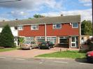 Terrace of two-storey houses: Lamda, Maloor and Copthorne.
Left-hand house has white fascia. The others have tile-hung area at first-floor level.
Driveways with cars.