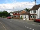 Road with houses on the far side.
Parked cars.
Telephone and power poles.