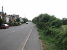 Looking south on Marsh Lane.
Houses on the left.
Footway and hedge on the right.
Sign warning of road junction.