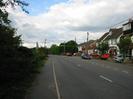 Looking north on Marsh Lane.
Hedge and footway on left.
Road with parked cars and houses on the right.