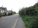 Looking south on Marsh Lane.
Houses on the left.
Footway and hedge on the right.
Warning sign: "REDUCE SPEED NOW" in verge on right.