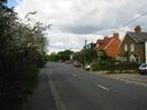 Looking north on Marsh Lane.
Hedge and footway on the left.
Road with houses on the right.