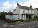 White painted house with slate roof.
Garage on left has light blue door.
Low wall with iron railings.