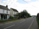 Looking south on Marsh Lane.
White-painted houses on left.
Footway and hedge on right.