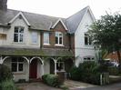 Row of houses with high pitched roofs.
Continuous porch along the front with arched timber supports.
Mixture of patterned brickwork and painted render.