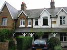 Row of houses with high pitched roofs.
Continuous porch along the front with arched timber supports.
Mixture of patterned brickwork and painted render.
Inset stone tablet reads "1893 Ye Meads".