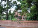 Low brick wall with trees and house behind.