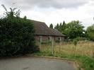 Road end with fence and bungalow in the background.