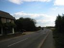 Looking south on Marsh Lane.
Dee Works on left. Dark trees either side of road, opening out in the distance.