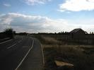 Looking south on Marsh Lane.
Road on the left with footway.
Scrubby area and small building on the right.
Bridge over Jubilee River in the distance.