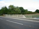 Road across Jubilee River bridge.
Footway and railings.
Trees in the distance.