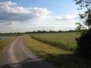 Wide path with river on left.
Scrubby field on right with trees on horizon.