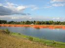 River with orange mesh enclosures on far side.
Trees in the background.