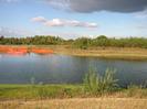 River with orange mesh enclosures on far side.
Trees in the background.