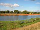 River with orange mesh enclosures on far side.
Trees in the background.