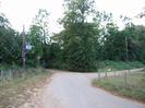 Road junction with electricity supply pole on left and trees in the background.